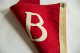 Detail of vintage red felt pennant, white letter B, with folds and minor discoloration.