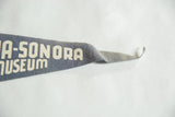 Vintage gray-blue felt pennant showing 'SONORA MUSEUM' text and tapering tip.