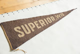 The full length of an antique brown felt pennant laid next to a hand-drawn ruler.
