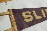 A dark stain and stitched tan letters on the antique purple felt pennant.