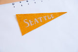 Golden yellow felt pennant with 'SEATTLE' lettering and aged wool texture.