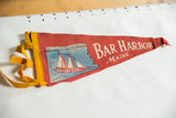 Yellow felt ties and aged red fabric of vintage Bar Harbor pennant.