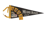 Vintage 1957 Miami Beach felt pennant with black base, yellow trim, beach scene.