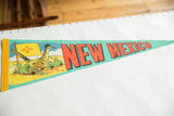 Vintage turquoise felt pennant featuring roadrunner, Zia sun flag, and red NEW MEXICO text.