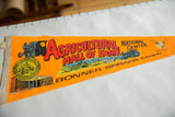 Orange felt souvenir pennant with 'Agricultural National Center' text, tractor, and bull.