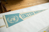 Blue United Nations emblem and cream ties on a vintage felt pennant.