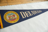 Colorful Great Seal and beige DELAWARE text on a dark blue felt vintage pennant.