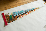 Detail of vintage felt Grand Canyon pennant showing colorful illustration and red edge.