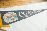Blue felt pennant with cream 'OCEAN BLUFF Mass.' text and colorful sailboat graphic.
