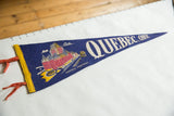 Blue felt vintage Quebec pennant featuring Chateau Frontenac illustration and bold white text.