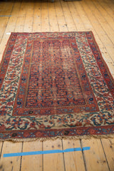 Vintage Malayer rug's raspberry Herati motif, ivory meandering vine border, and visible pile wear.