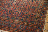 Vintage Malayer rug corner with brick red and blue Herati motif, intricate borders, and visible wear.