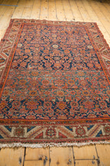 Malayer rug's intricate geometric border, fringe, and Herati motif field in madder red and blue.