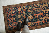Antique Mahal Fereghan fragment with navy, red, ivory patterns, worn pile, tattered edges.