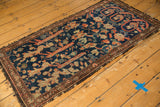 Antique Fereghan rug fragment's tattered end, worn navy pile, and intricate madder root red border.