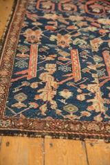 Antique Persian Fereghan fragment: Worn hand-knotted pile with madder red, navy patterns, and tattered edge.