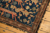 Antique Fereghan rug corner showcasing navy blue field, intricate madder root red patterns, and tattered edge.