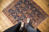 Repeating vinery and oversize floral motifs on the antique Afshar rug's indigo field.