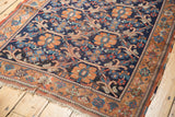 Antique Afshar rug's navy field and rust border, showing repeating floral vinery and aged texture.