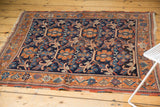 Antique Afshar rug corner showcasing rust border, navy field's floral vinery, and tattered ends.