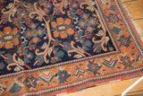 Antique Afshar rug corner with indigo floral vinery field, rust geometric border, tattered fringe.