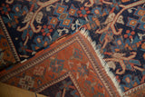 Antique Afshar rug corner detail, revealing indigo vinery patterns, rust border, and visible fringe wear.