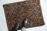 Vintage Sarouk rug mat with a concentric diamond medallion and dense florals in red and beige on navy.