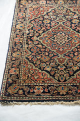 Corner of a vintage Sarouk rug showing its floral border and original plain woven end.