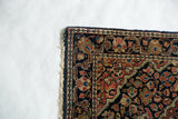 Corner of a vintage Persian Sarouk rug with its original plain woven end and secured side.