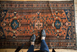 Vintage Kurdish Hamadan rug's geometric pattern in madder red and navy, showing low pile wear.