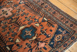 Vintage Hamadan rug with terracotta and navy geometric pattern, showing low pile and faint foundation.