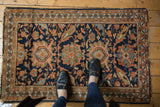 Vintage Hamadan rug's central navy blue field with oversized blush and green floral motifs.