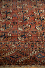 Geometric border and gul motifs in dusty brick red and navy on this antique Tekke rug.