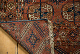 Tekke rug corner folded, showing hand-knotted foundation, secure overcast edge, and natural fringe.