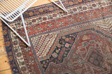 Antique Qashqai rug's border showing madder red, navy, ivory traditional motifs and mostly even wear.