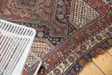 Antique Qashqai rug with madder red, navy, antique ivory borders and light tatter.