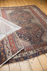 Antique Qashqai rug corner with madder red geometric border, navy details, light tatter.