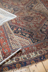 Antique Qashqai rug section: rich madder red, navy, ivory patterns, visible pile wear.