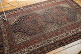 Antique Qashqai rug corner showcasing madder root red field, navy border, delicate floral motifs, and light tatter.