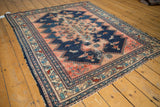 Hard wear, tattered edge on vintage Malayer rug in navy blue and blush with floral borders.