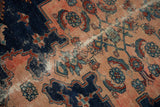 Close-up of worn vintage Malayer rug showing navy, blush floral motifs, and visible foundation.