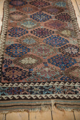Antique Belouch runner featuring repeating geometric gul motifs, an intricate border, and tattered kilim end.