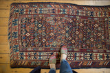 Antique Caucasian rug with geometric motifs, low pile texture, and time-softened navy, rose, ivory hues.