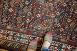 Close-up of geometric boteh and serpent motifs with time-softened tones and low pile.