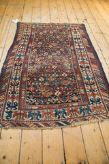 Corner detail of antique Caucasian rug, featuring geometric borders, rich blues, and fringed end.