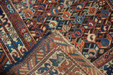 Antique Caucasian rug showing its dense geometric pile, woven foundation, and rich dark blue selvedge.