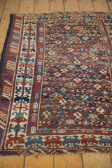 Vibrant hand-knotted tribal border and geometric field pattern on an antique Caucasian rug.