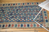 Geometric floral cross sections on the antique Kuba runner's blue field, with patterned border.