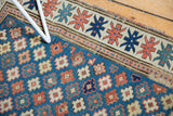 Sky blue geometric floral field, antique ivory star border, and the runner's worn edge.