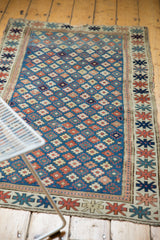 Antique Kuba runner corner showcasing geometric star motifs, tattered edge, and blue field.